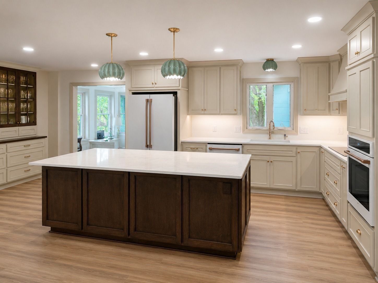 Bright modern kitchen with a large island, white cabinetry, stainless steel fridge, and pendant lights.