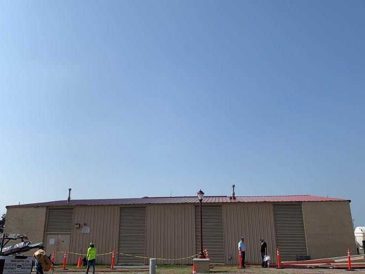 Several people stand outside a long tan building under a clear blue sky.