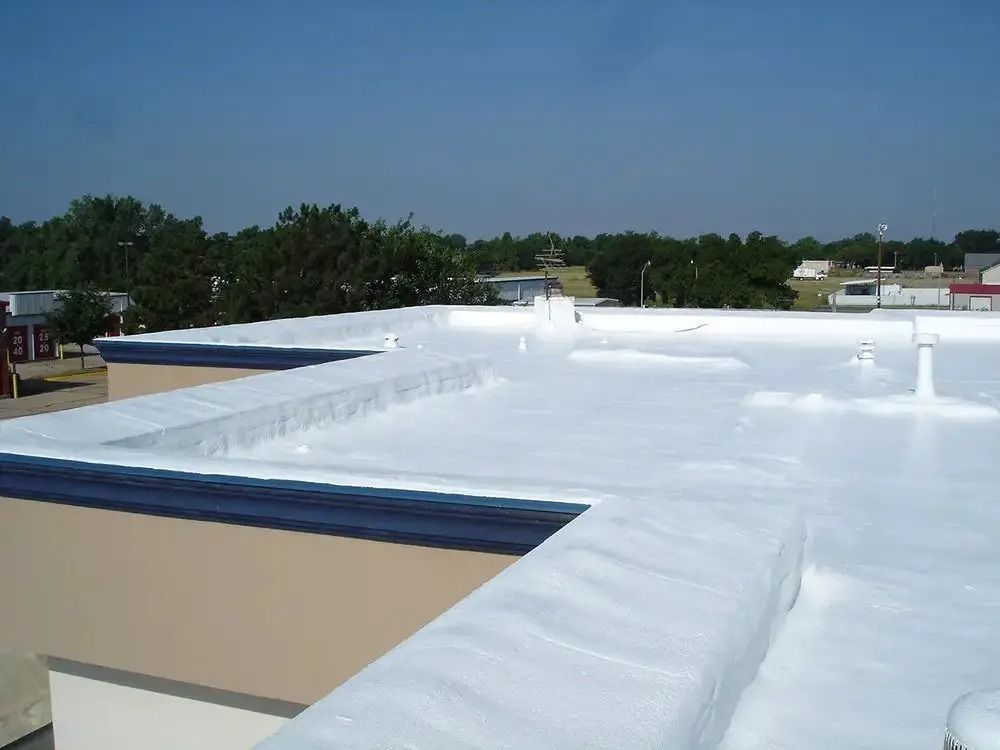 Flat white rooftop with HVAC units under a clear blue sky, seen from above