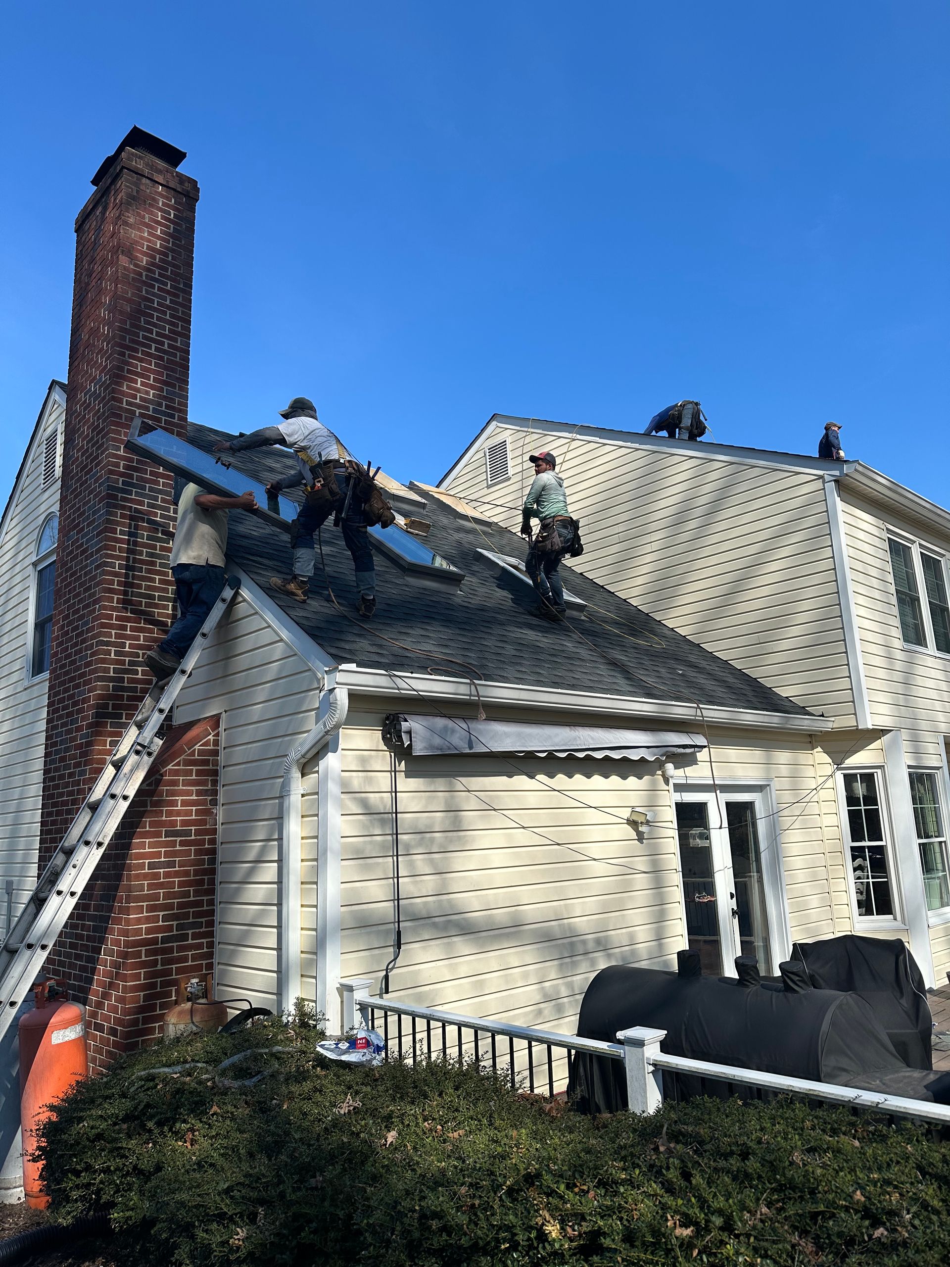 Severely fire-damaged house with a charred roof, blackened chimney, and debris in the yard