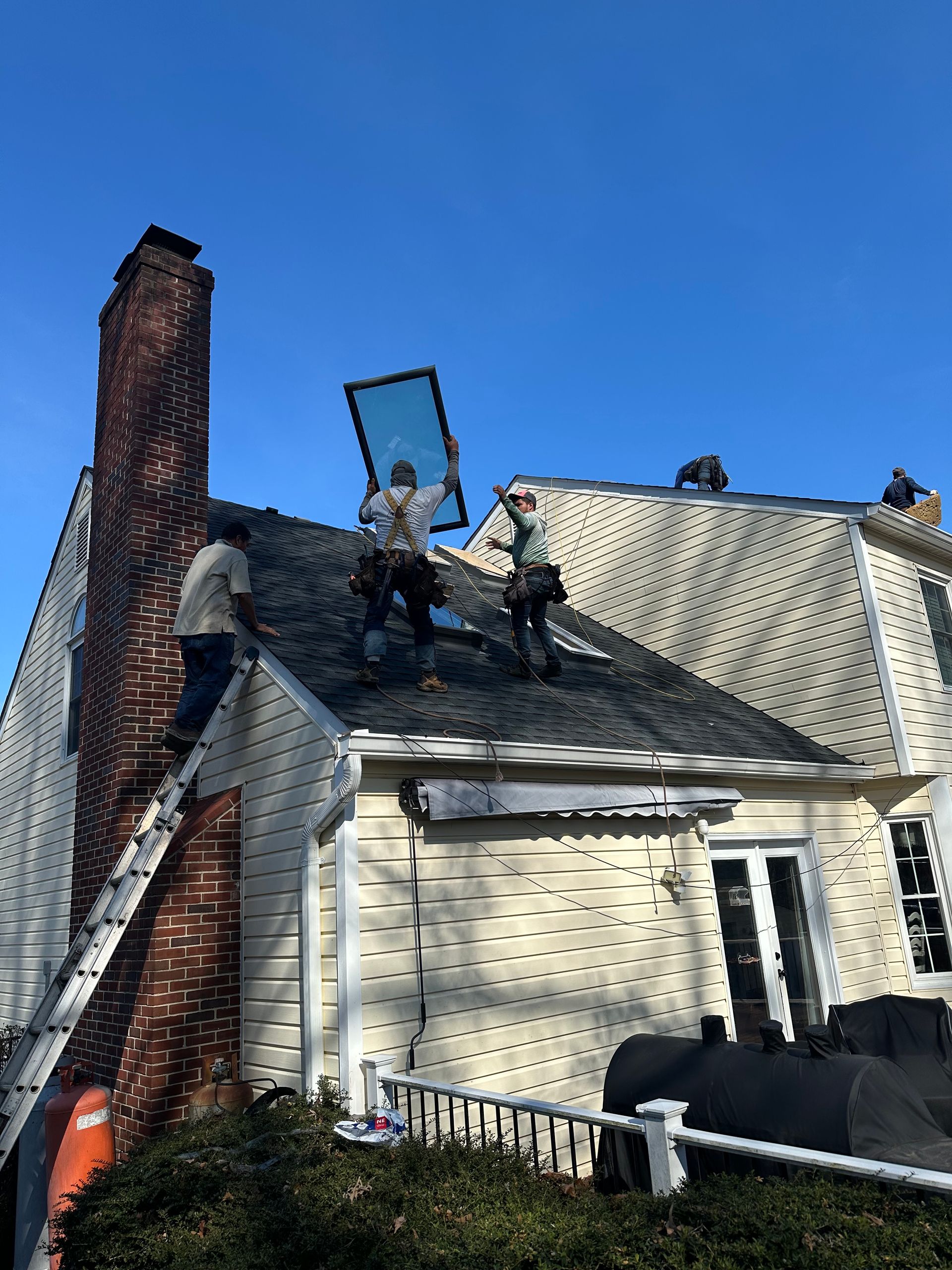 Damaged house roof with a collapsed chimney and visible smoke damage under a clear blue sky