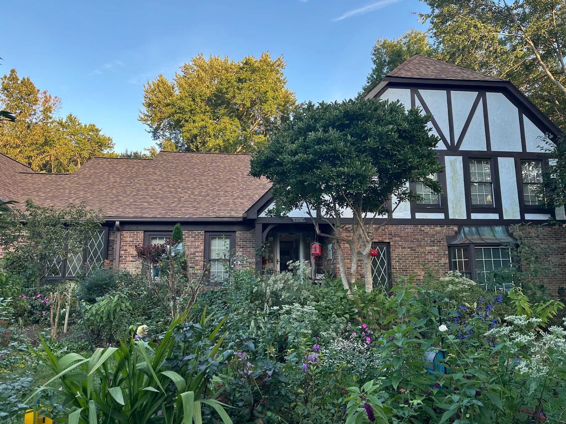 Tudor-style house with garden flowers and greenery under a blue sky