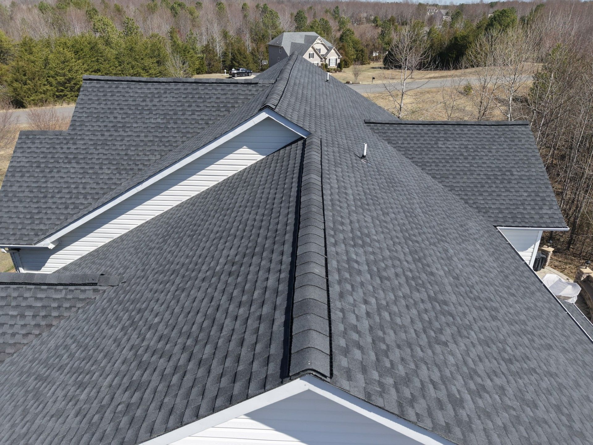 Gray shingle roof with multiple gables and a central ridge on a house, viewed from above