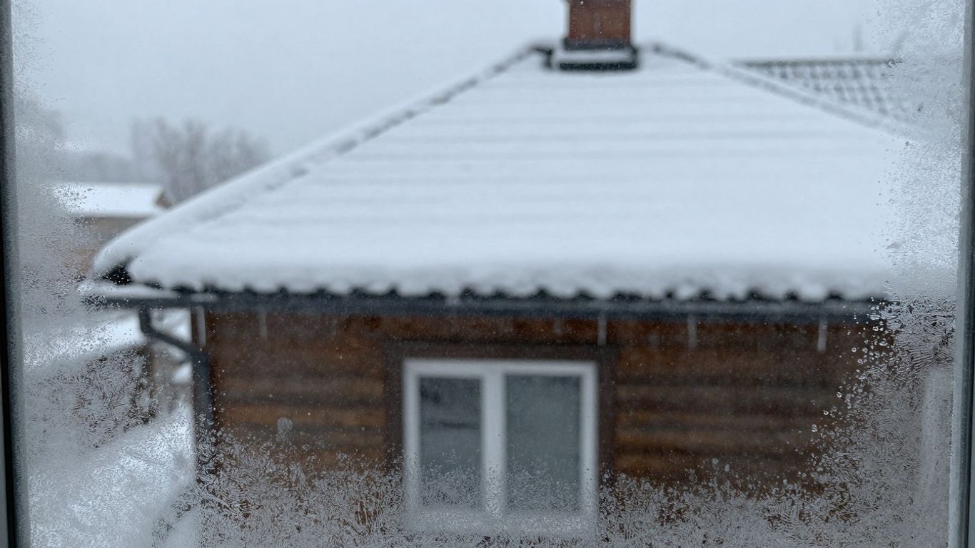 Snow-covered house roof and windows during a heavy snowfall.