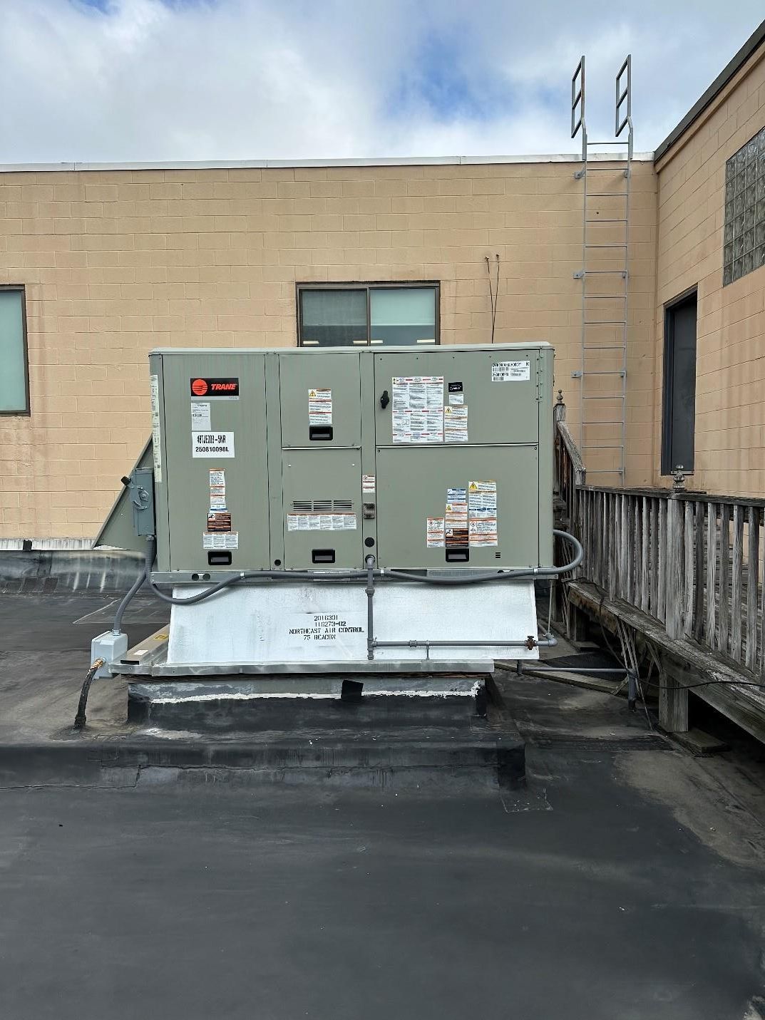 HVAC unit on a commercial building rooftop, with a ladder in the background.
