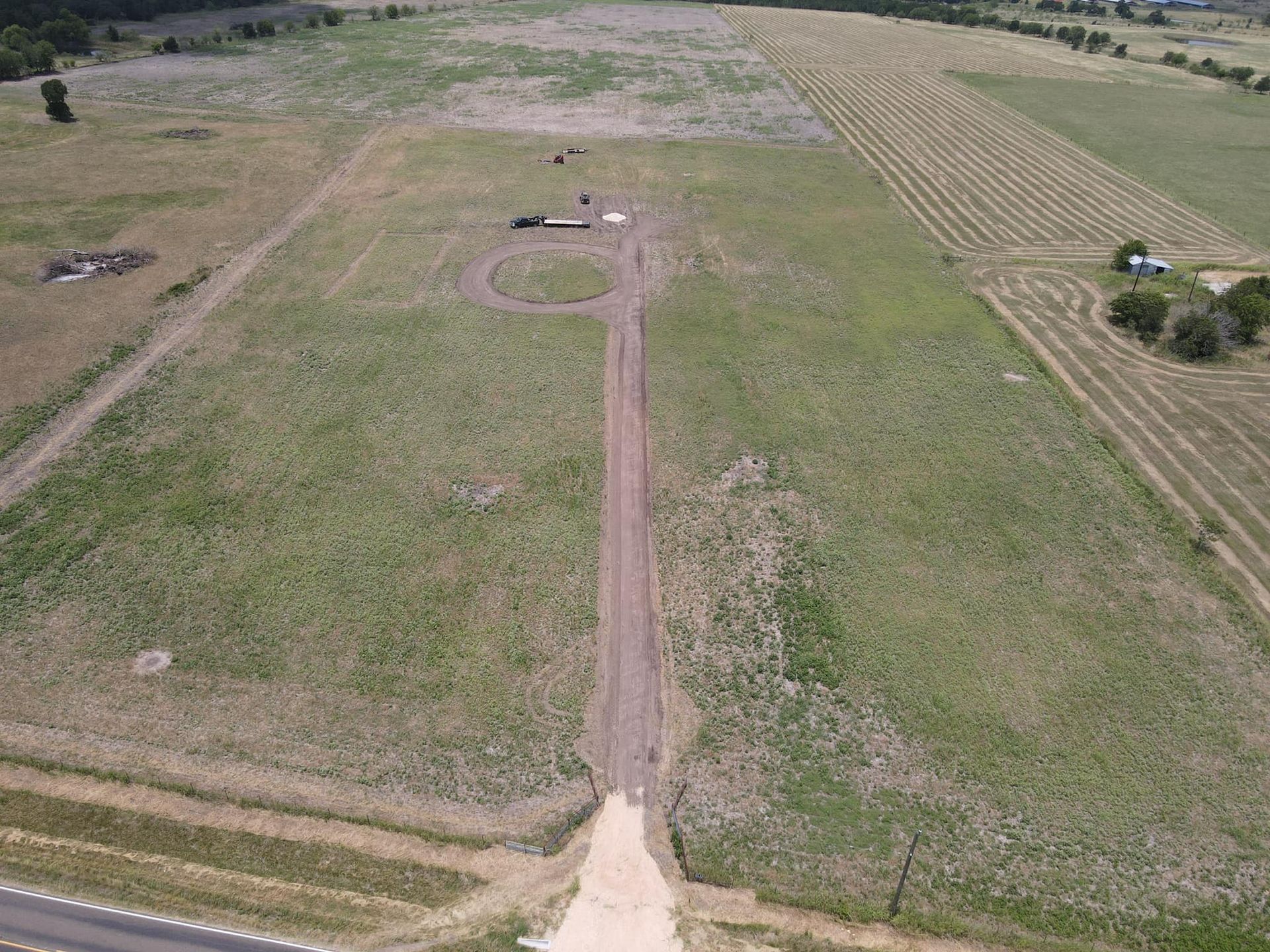 Aerial view of a dirt road leading to a circular area in a grassy field.