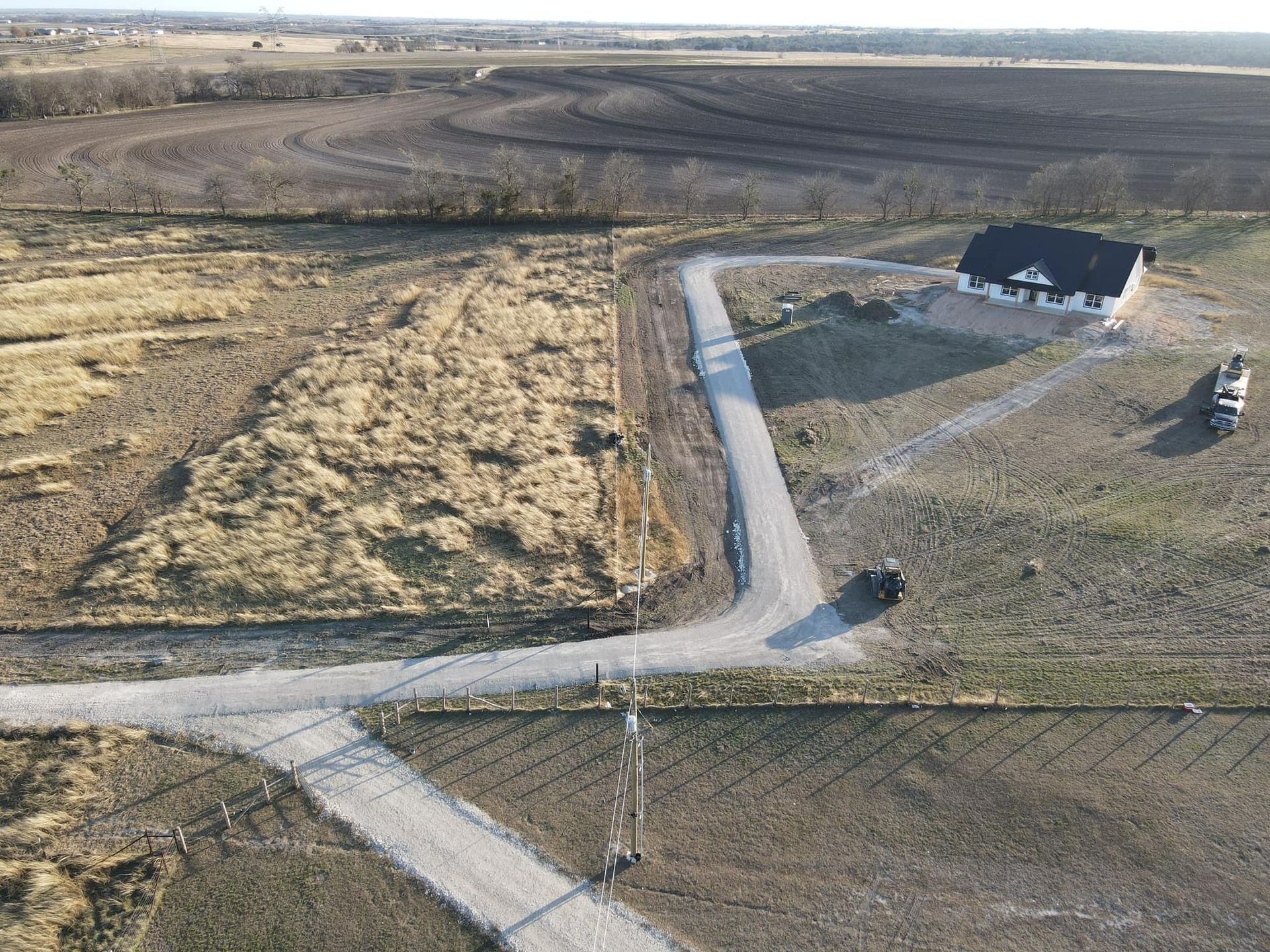 An aerial view of a house under construction, with access roads in a rural landscape.