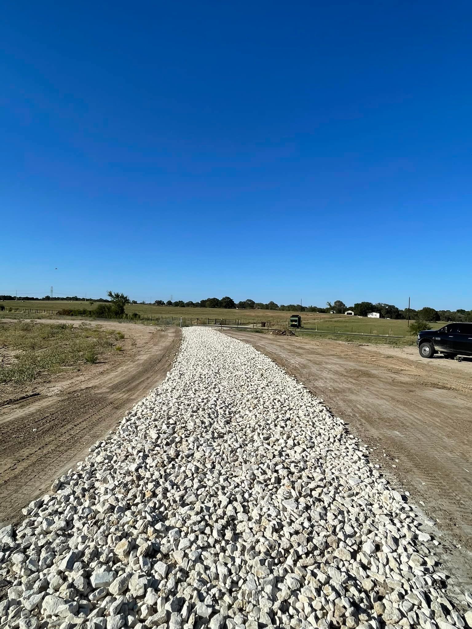 A gravel road stretches into the distance under a bright blue sky.