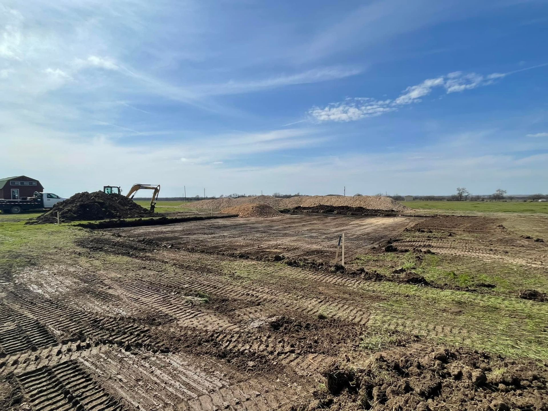 Construction site with an excavator moving dirt under a blue sky.