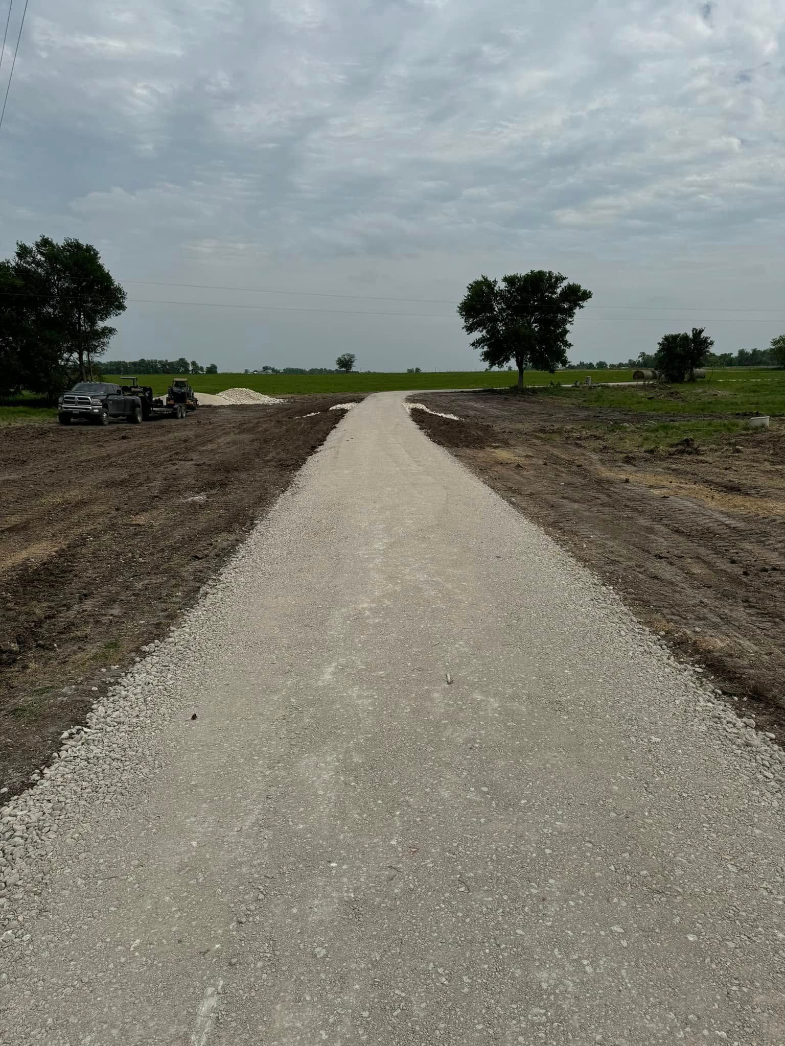 Gravel pathway through a field, under a cloudy sky.