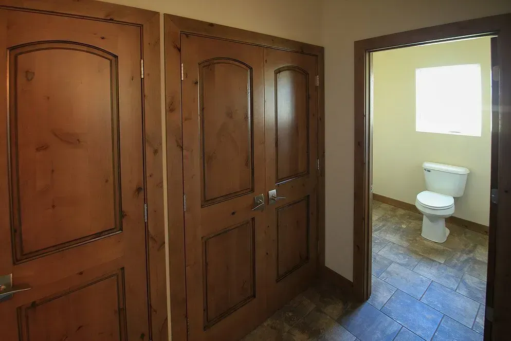 A bathroom with a toilet and two wooden doors