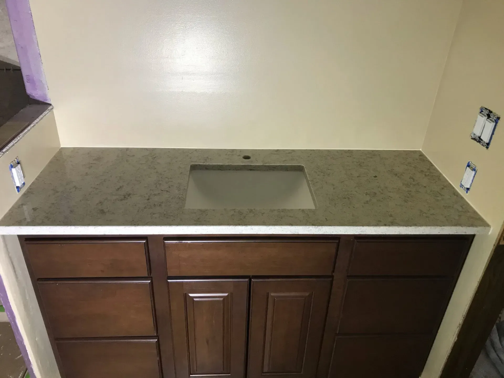 A bathroom vanity with a sink and wooden cabinets.