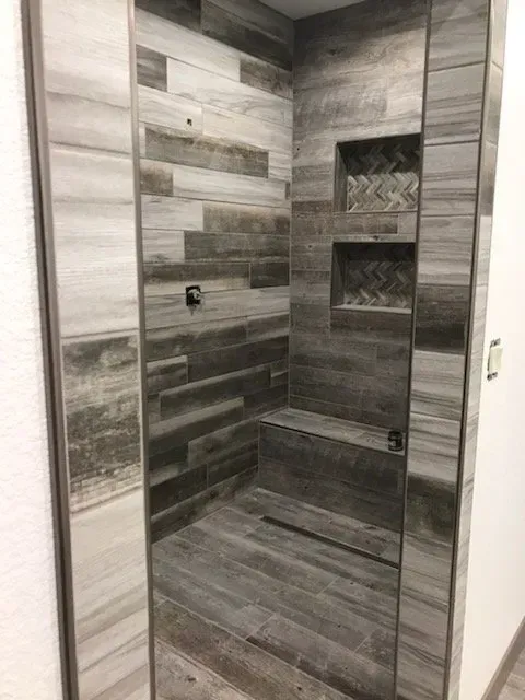 A bathroom with a walk in shower and a bench.
