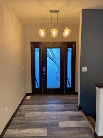 A hallway with a door and a light hanging from the ceiling.