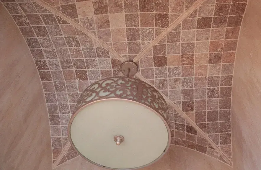 A lamp is hanging from the ceiling of a room with a tiled ceiling.