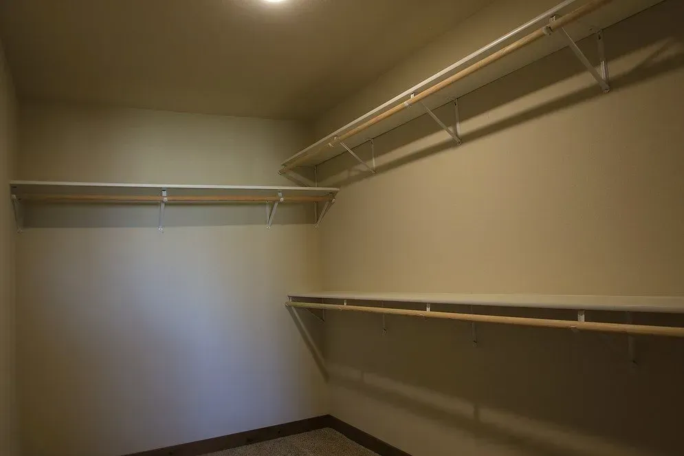 An empty walk in closet with shelves and clothes racks.