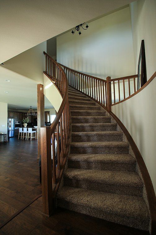 A curved staircase in a house with a wooden railing