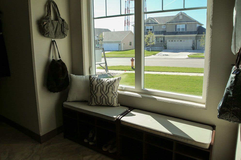 A room with a bench and a window with a view of a house.