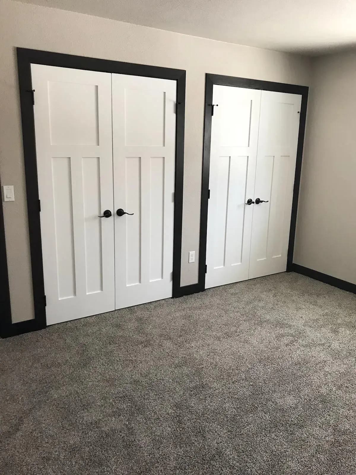 A bedroom with two white doors and a carpeted floor.