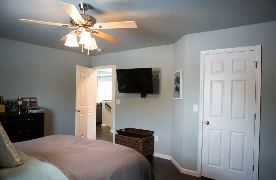 A bedroom with a bed , ceiling fan , television and dresser.
