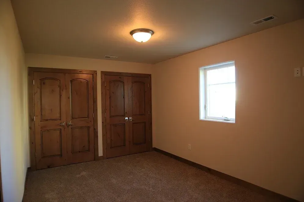 An empty room with two doors and a window.