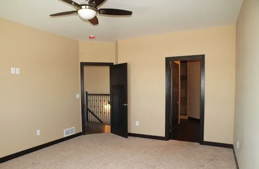 An empty room with a ceiling fan and two doors