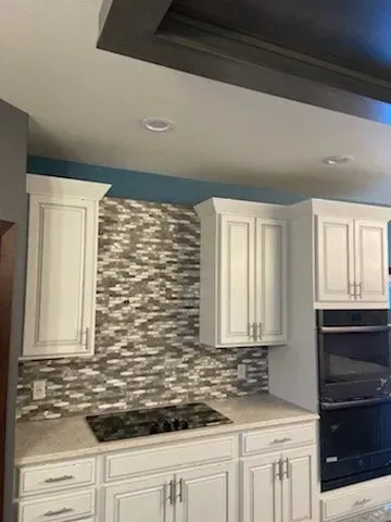 A kitchen with white cabinets and a stove top oven.