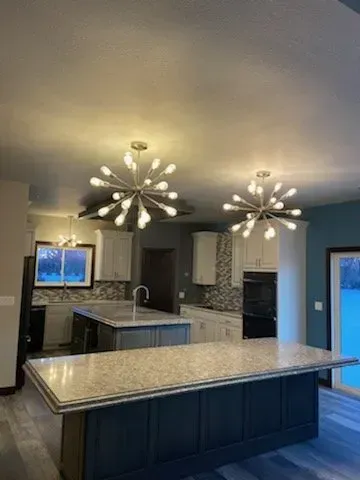 A kitchen with a large island and two chandeliers hanging from the ceiling.
