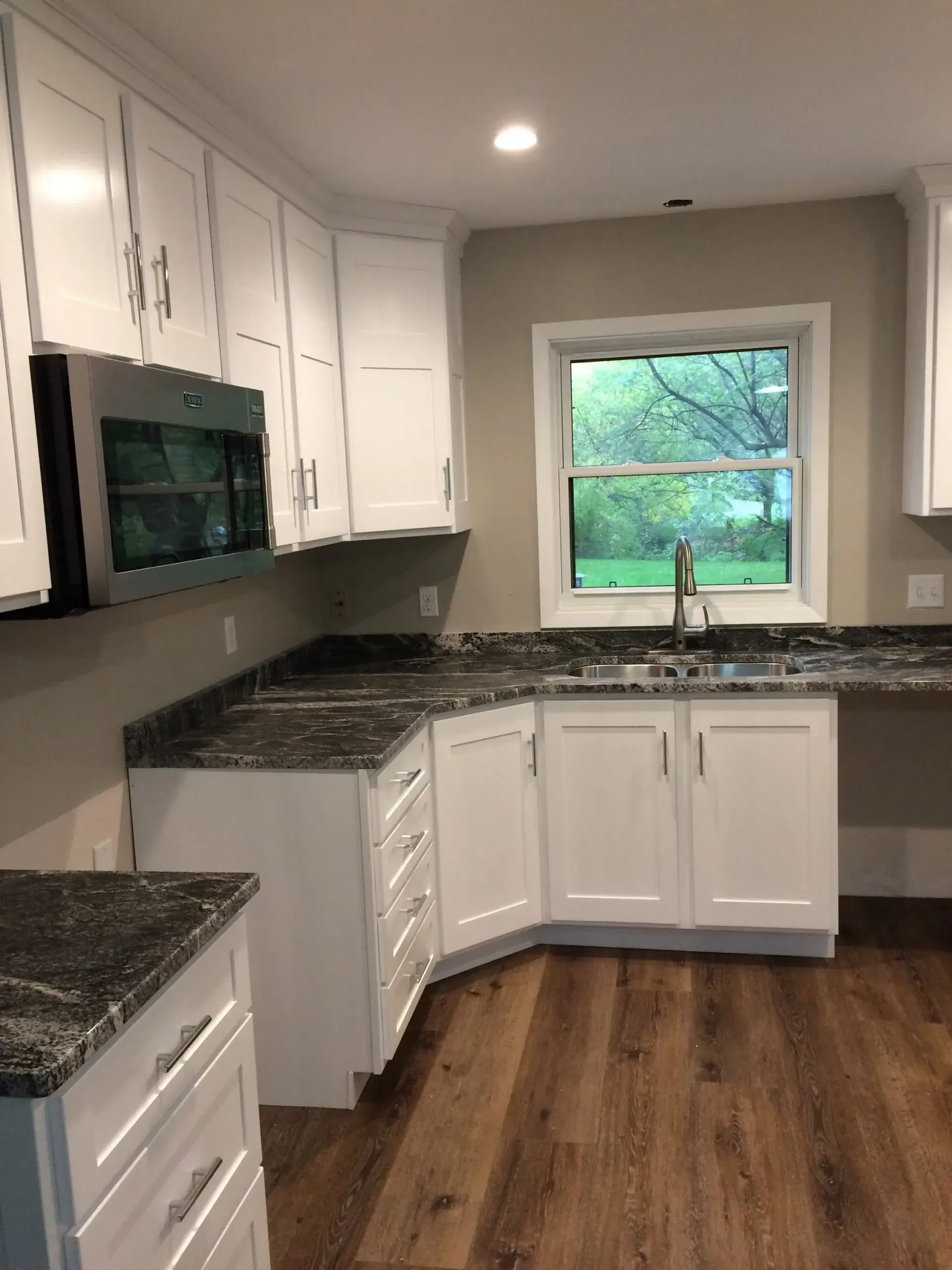 A kitchen with white cabinets and granite counter tops.