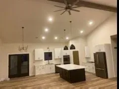 A kitchen with a large island and a ceiling fan.