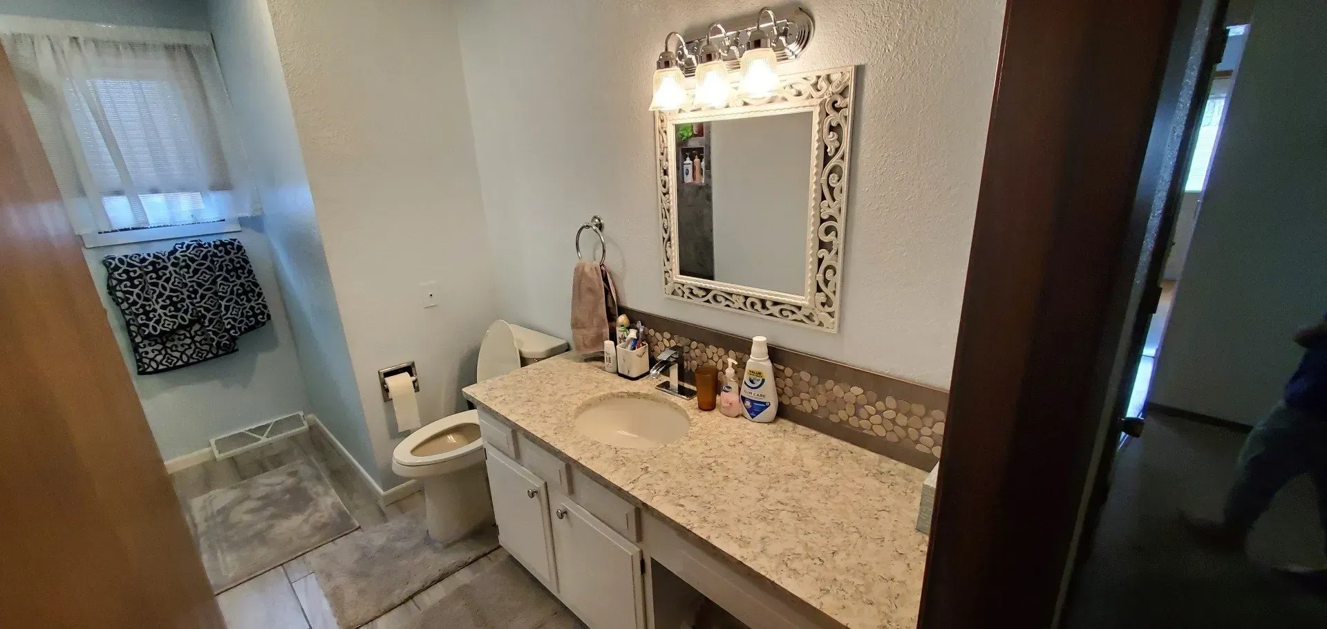 A bathroom with a sink , toilet and mirror.
