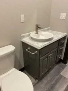 A bathroom with a toilet , sink and vanity.