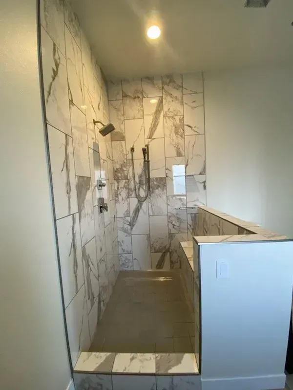 A bathroom with marble tiles and a walk in shower.