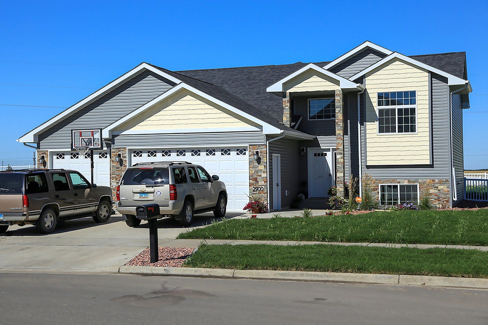 Two cars are parked in front of a large house