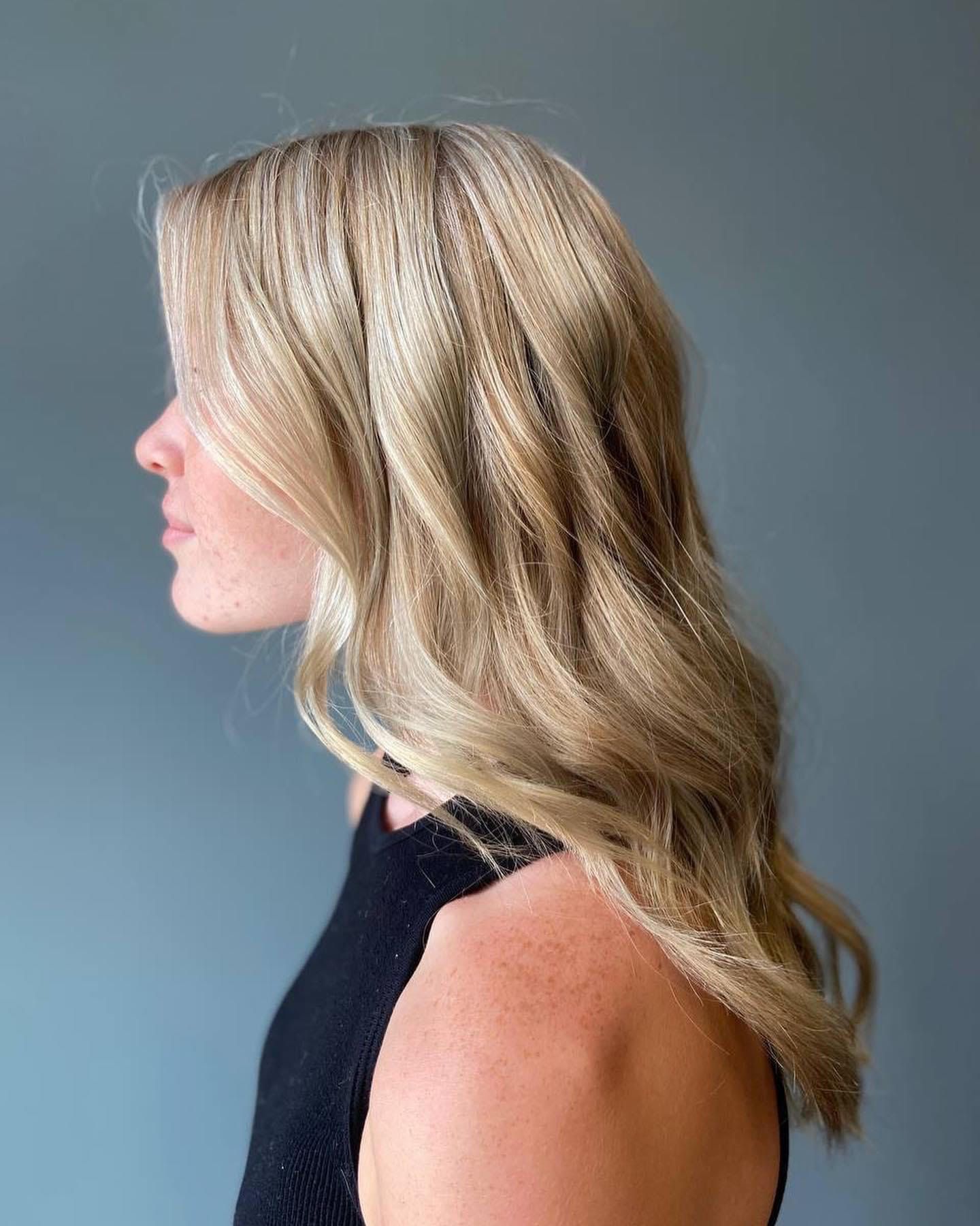 A woman with long blonde hair is wearing a black tank top.