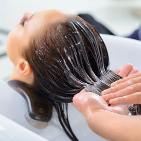 A woman is getting her hair washed in a sink at a salon.