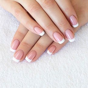 A close up of a woman 's nails with pink and white french manicure.