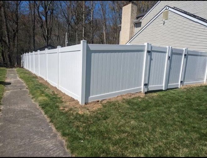Black metal fence surrounding a pool and yard, with trees in the background.