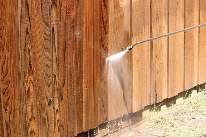 Black metal fence surrounding a pool and yard, with trees in the background.