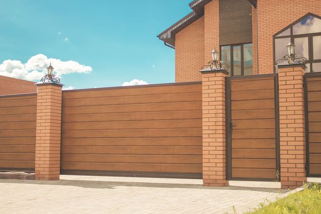 White picket fence along a beige house with a curved design.