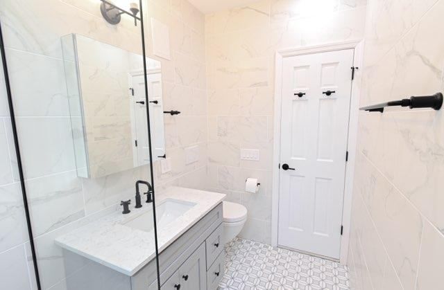 A bathroom with a sink , toilet , mirror and walk in shower.