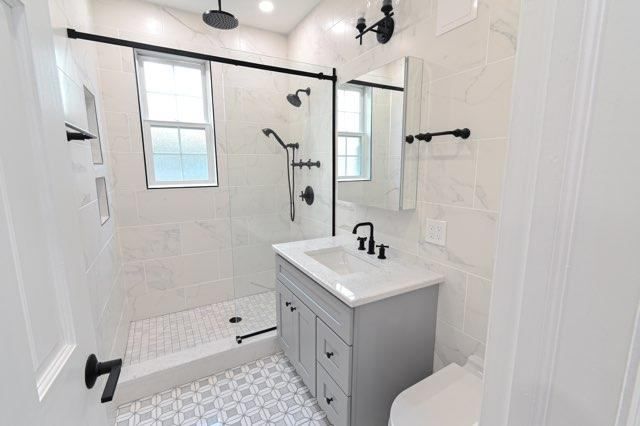 A bathroom with a sink , toilet , shower and window.