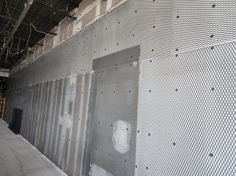 A wall with a mesh covering is being built in a building.