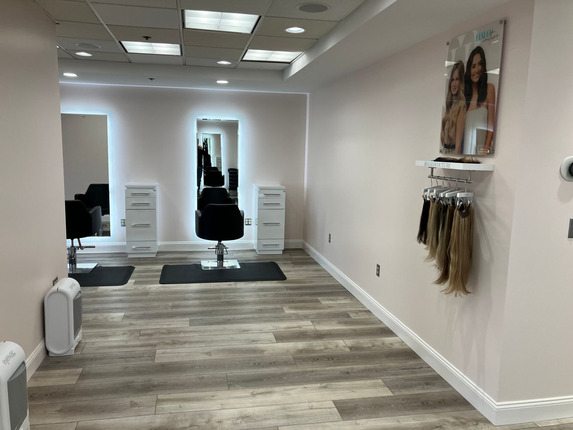 A hair salon with chairs , mirrors , and a display of hair extensions.