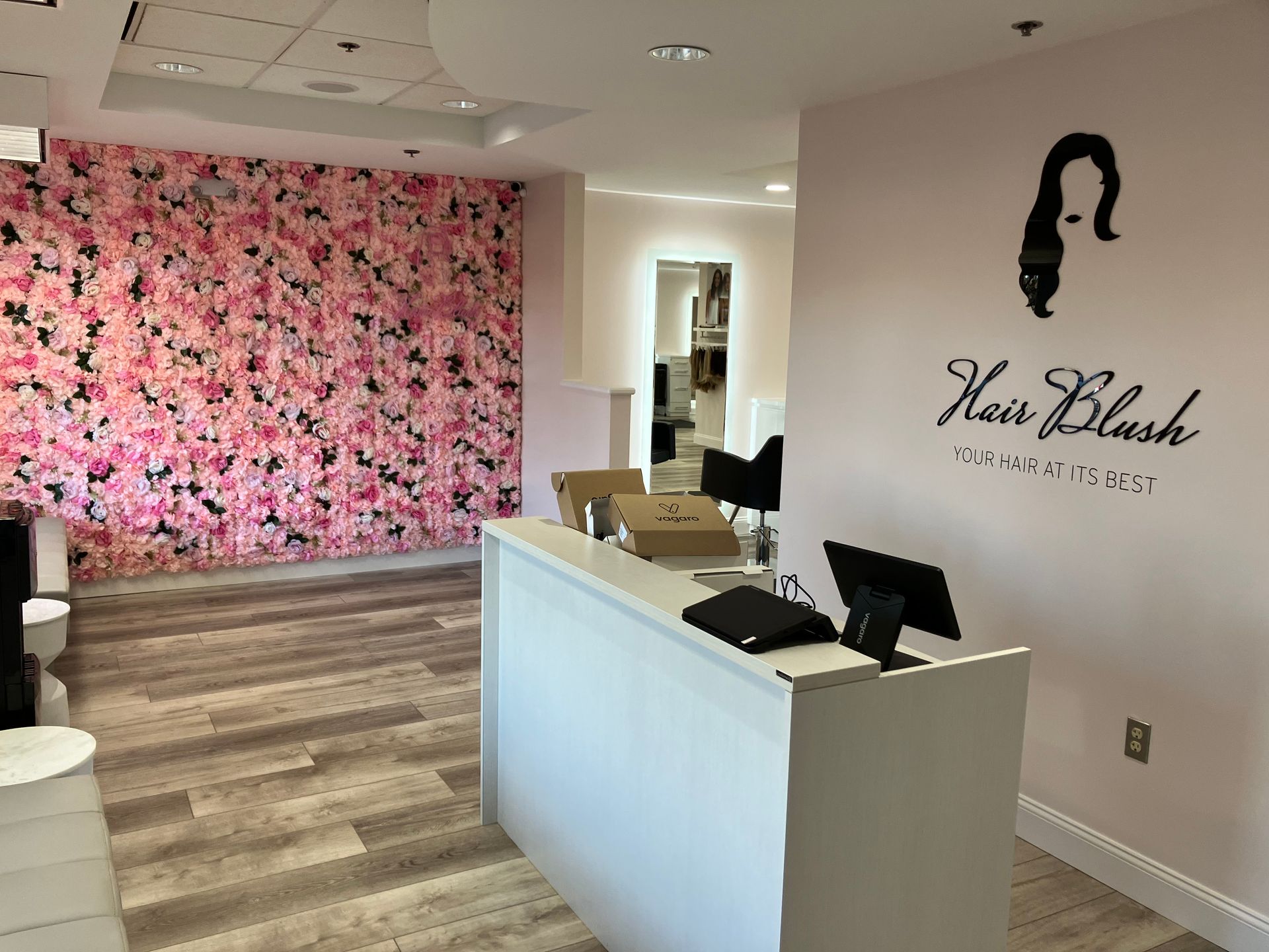 A hair salon with a pink wall and a white counter