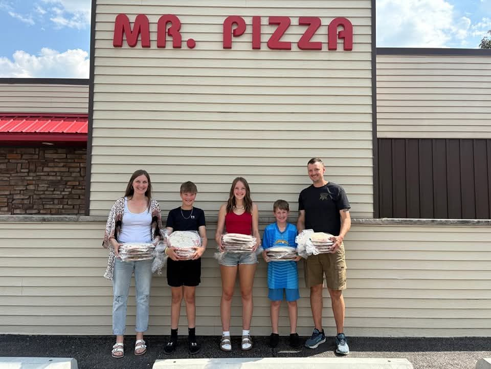 Five people holding pizza boxes stand outside a Mr. Pizza restaurant.