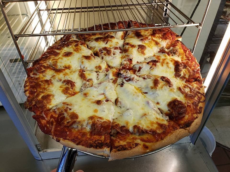 Cheesy pizza on a metal rack in an oven, with browned crust and melted mozzarella.