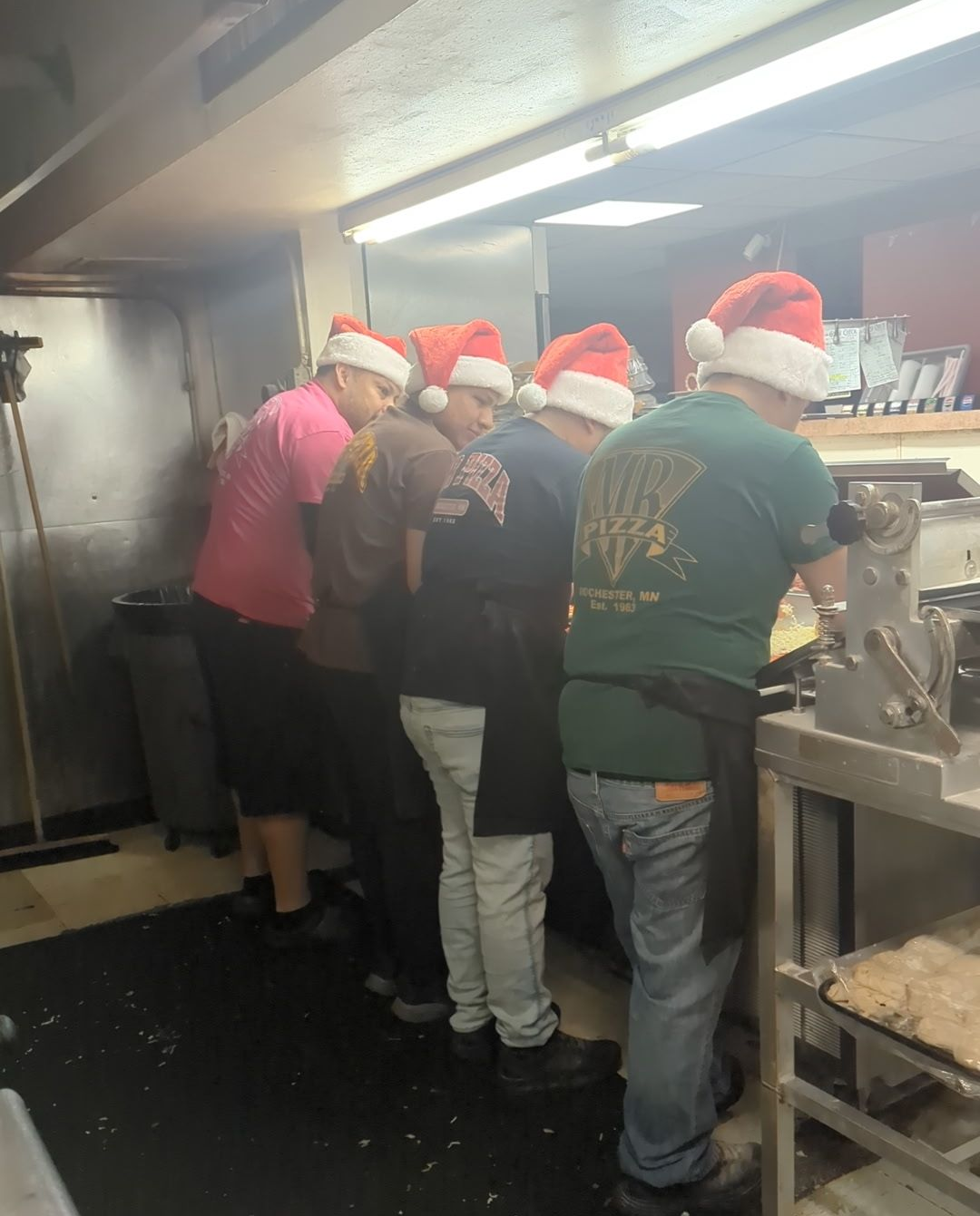 People in Santa hats serving food at a busy kitchen counter