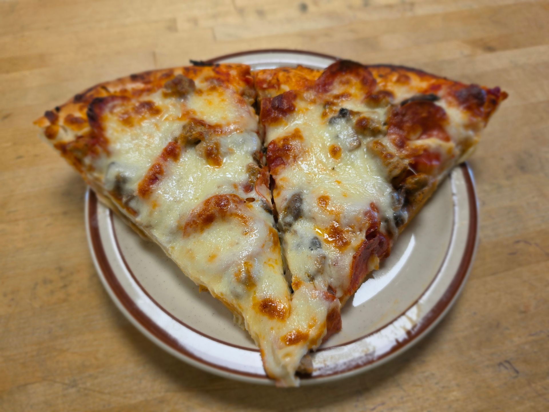 Two slices of cheese pizza on a small plate on a wooden table