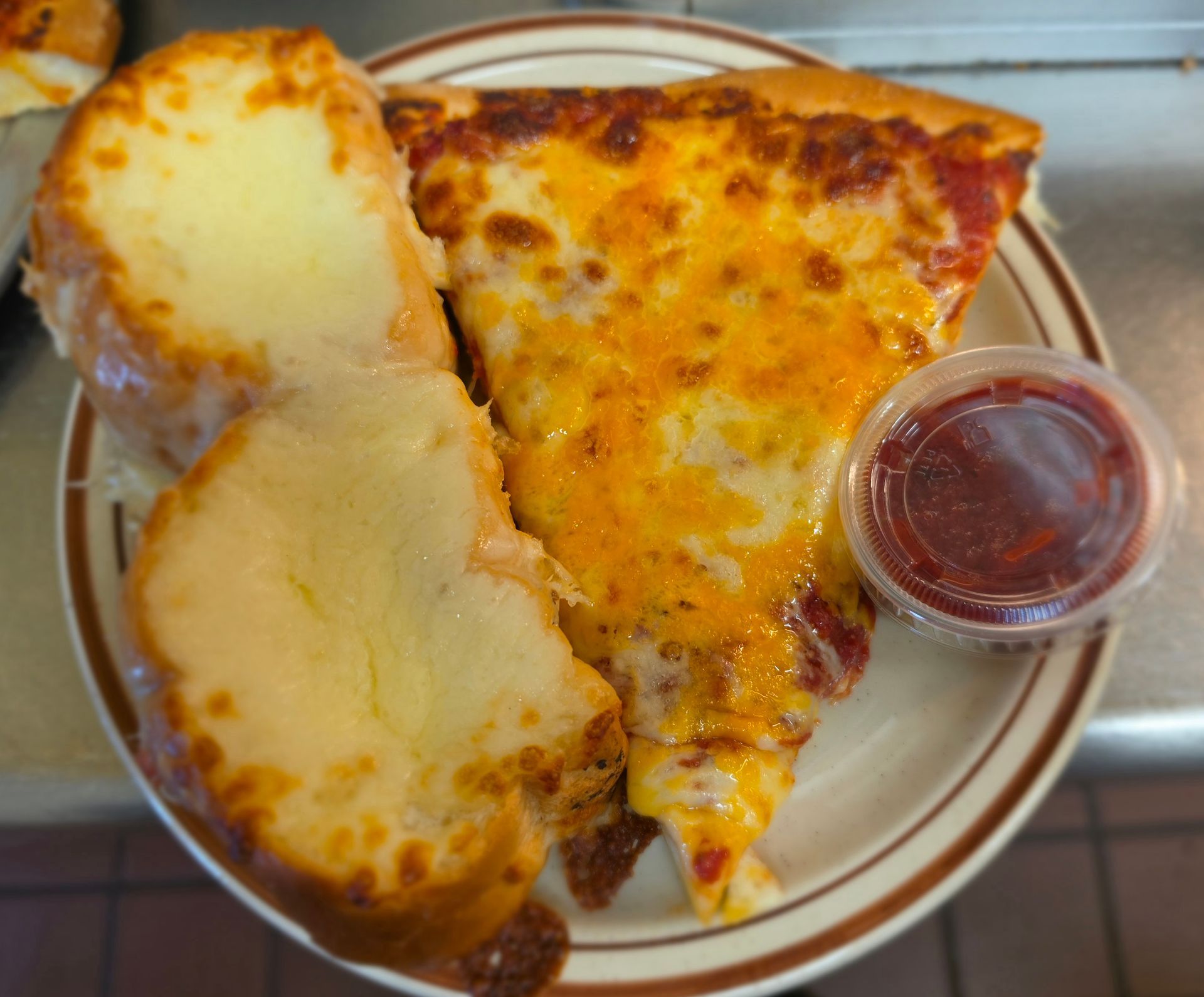 Cheese pizza slice with garlic bread and marinara sauce on a plate